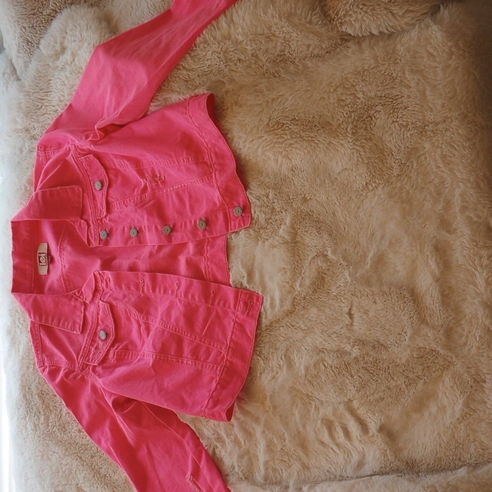 A distressed neon pink acid wash jean jacket.
